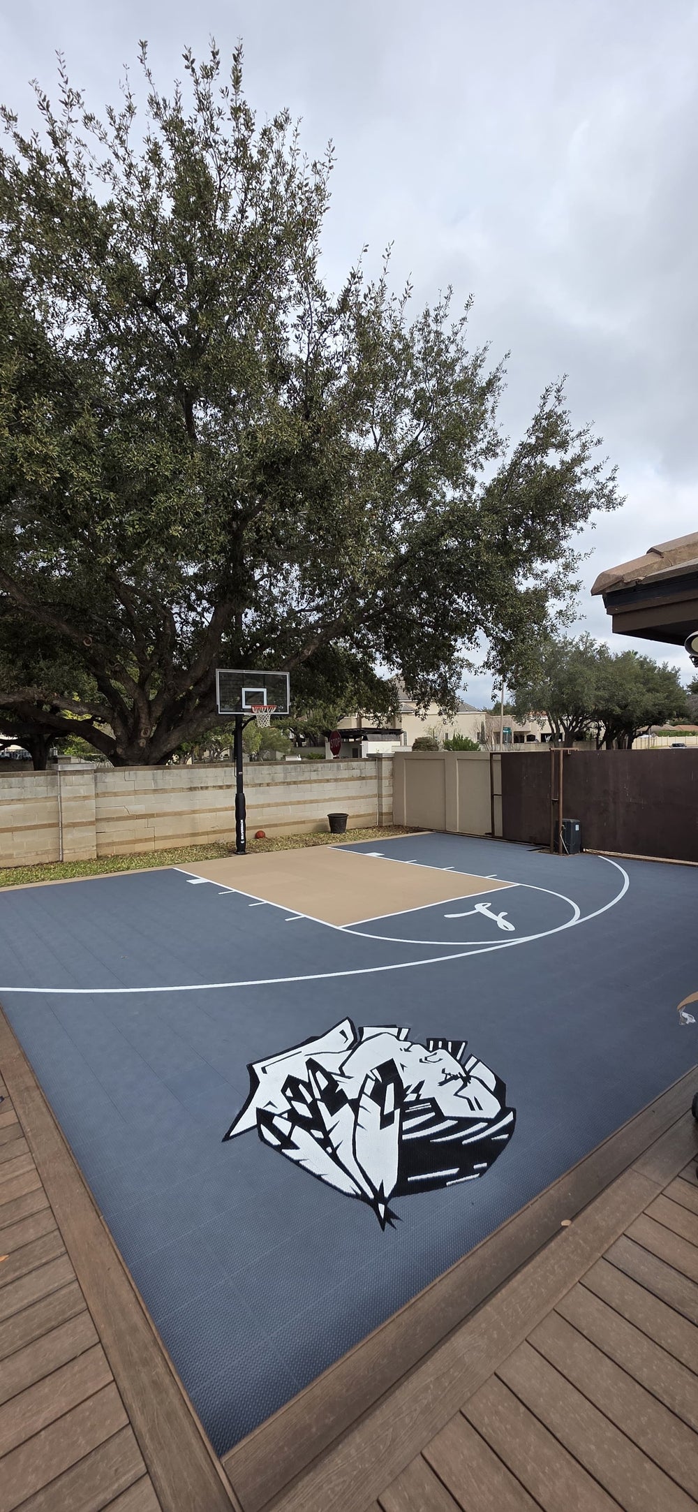 Small outdoor backyard modular basketball court. Featuring two custom logos and in-ground basketball hoop. 